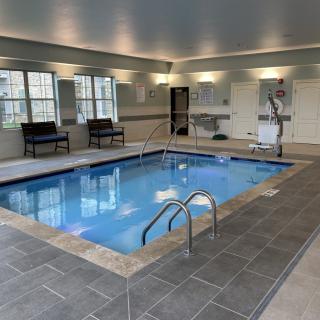 A modern indoor swimming pool with seating and bright overhead lighting.