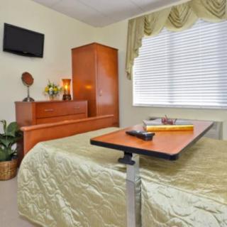 A cozy bedroom with a television, wooden furniture, and a window with curtains.