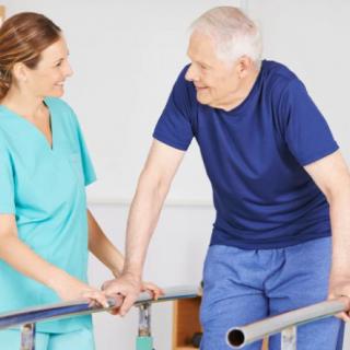 A nurse assists an elderly man with walking exercises in a rehabilitation setting.