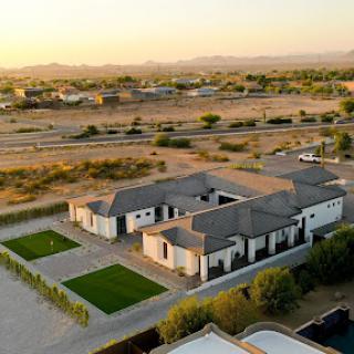 A stunning aerial view of a modern house surrounded by scenic landscapes during sunset.