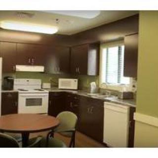 A cozy kitchen interior with appliances, a table, and chairs.