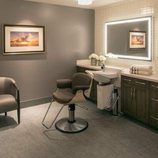 A well-lit salon interior with a modern chair, sink, and decorative elements.