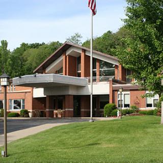 A modern brick building surrounded by well-maintained grass and landscaping, featuring an American flag.