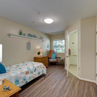 A cozy bedroom with a single bed, a wicker chair, and bright decor.