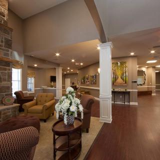 A spacious and elegantly designed living room featuring comfortable furniture, decorative flowers, and artwork on the walls.