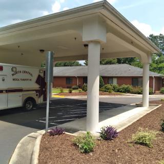 An ambulance parked under a covered area at a healthcare facility.
