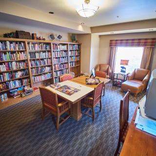 A cozy reading room with bookshelves, a table, and comfortable seating.