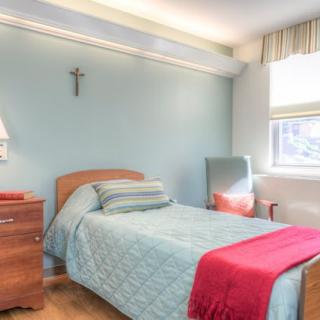 A cozy bedroom with a single bed, featuring light blue walls and wooden furniture.