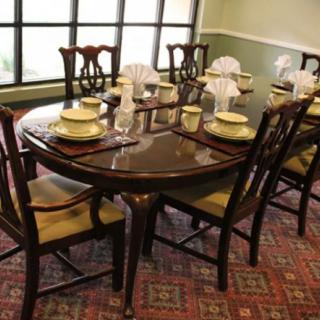 A formal dining table set with elegant place settings and surrounded by wooden chairs.