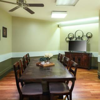 A warm and inviting dining room featuring a large wooden table, comfortable chairs, and a television for entertainment.