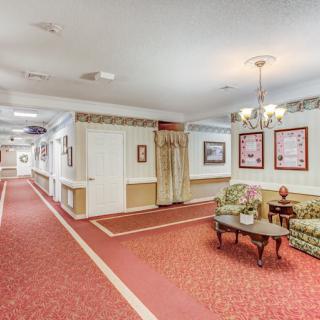 A well-lit hallway with a cozy seating area featuring sofas, a table, and decorative elements.