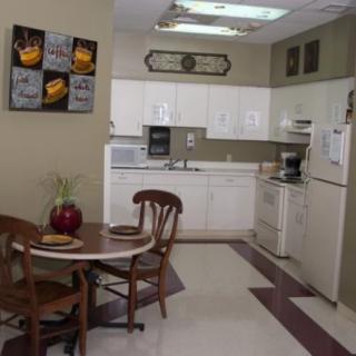A cozy kitchen with a small dining area featuring a round table and chairs, surrounded by white cabinets and standard kitchen appliances.