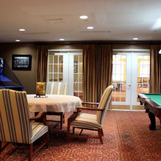 A cozy game room featuring a pool table and a round table with striped chairs.