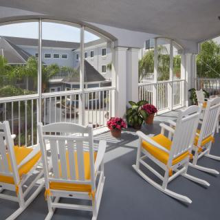 A cozy porch with white rocking chairs and vibrant flower pots, offering a serene outdoor escape.