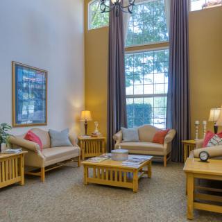 A cozy living room with sofas, coffee tables, and large windows.