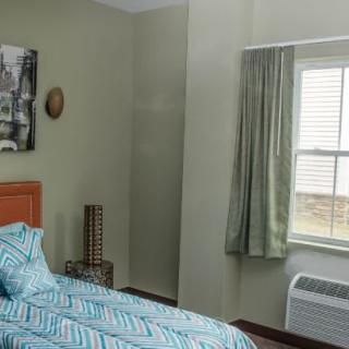 A cozy bedroom with teal bedding, a window with green curtains, and wall decor.