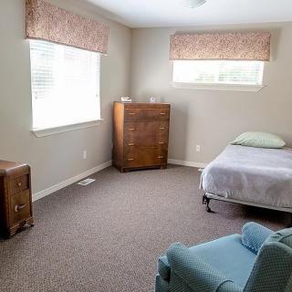 A simple bedroom with a single bed, dresser, and an armchair.