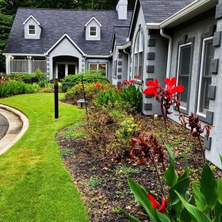A charming house with a beautifully landscaped garden featuring vibrant red flowers.