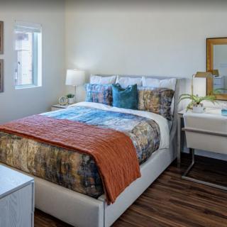 A modern and cozy bedroom featuring a neatly made bed, stylish decor, and a desk by the window.