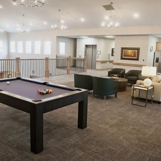 A modern lounge area featuring a pool table and comfortable seating.
