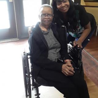 A joyful moment shared between an elderly woman in a wheelchair and her caregiver.