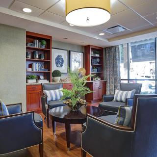 Stylish lobby area featuring comfortable seating, a central table with a plant, and bookshelves in the background.