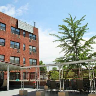 A brick building with outdoor seating and a tree under a clear blue sky.