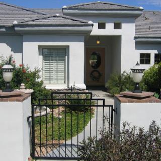 A modern house entrance featuring a black gate and well-kept garden.