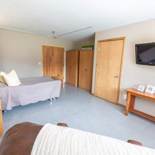 A minimalist bedroom with a modern design, featuring wooden doors and a wall-mounted TV.