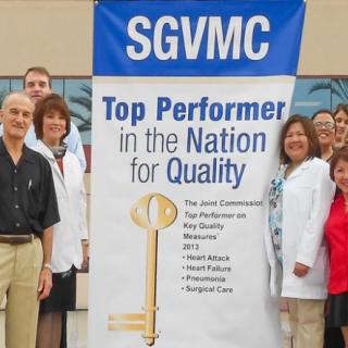 A group of healthcare professionals standing beside a banner recognizing SGVMC as a top performer in quality.