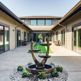 A modern courtyard with a unique fountain centerpiece and surrounding greenery.