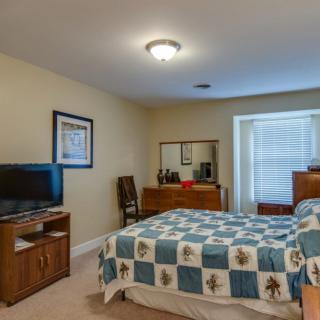 A cozy bedroom with a bed, dresser, and television setup.