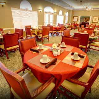 A neatly arranged dining room with red tablecloths and set tables, ready for guests.
