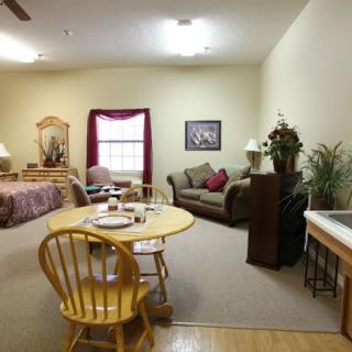 A cozy studio apartment featuring a combined living and bedroom space, with a dining table setup and warm furnishings.