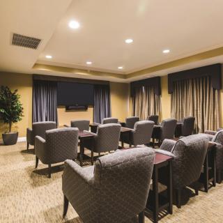 A well-furnished conference room with comfortable seating and a large television at the front.