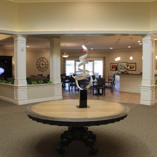 A welcoming lobby featuring a stylish round table with a sculpture, surrounded by seating areas.