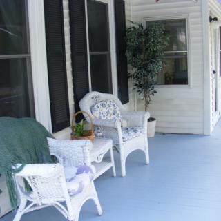 A cozy porch with wicker chairs and a potted plant, perfect for relaxation.