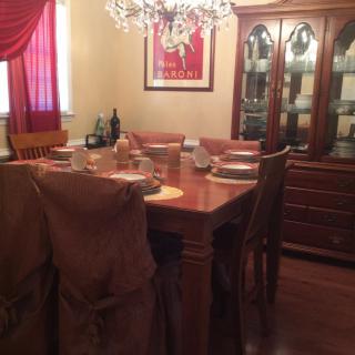 A cozy dining room with a wooden table and chairs set for dinner, illuminated by a chandelier.