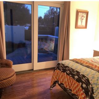 A cozy bedroom with a comfortable chair and a bed near large glass doors.