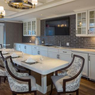 A modern kitchen and dining area featuring a sleek design with comfortable chairs, a large table, and contemporary lighting.