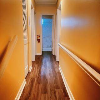 A residential hallway with yellow walls and wooden flooring.