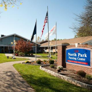 Entrance of North Park Nursing Center with flags and well-maintained landscaping.