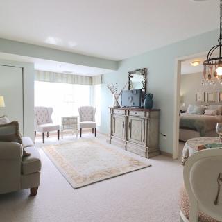 Bright and elegantly decorated living room featuring a sofa, chairs, and a decorative mirror.
