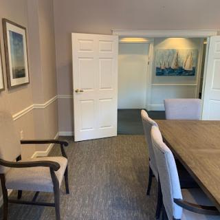 A spacious meeting room featuring a wooden table, comfortable chairs, and decorative wall art.