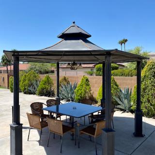 A cozy outdoor seating area under a gazebo, perfect for enjoying sunny days.