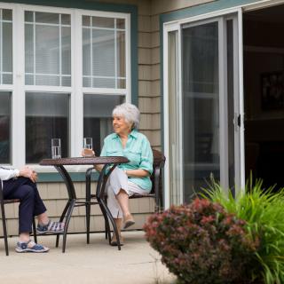 Two elderly individuals enjoying a conversation on a patio.