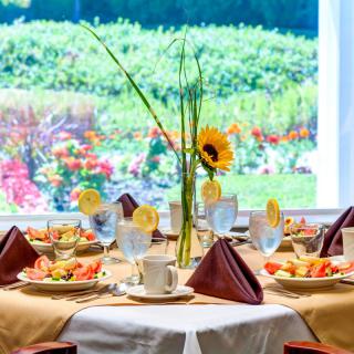 An elegantly set dining table with floral decor overlooking a vibrant garden.