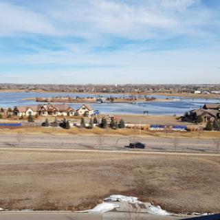 A serene view of a lake bordered by residential areas under a clear blue sky.