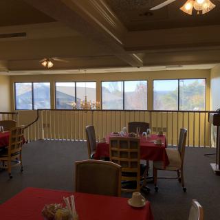 A cozy restaurant interior with red tablecloths and large windows offering a scenic view.