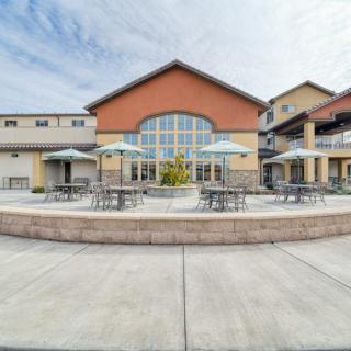 An outdoor patio area with tables and umbrellas in front of a commercial building.